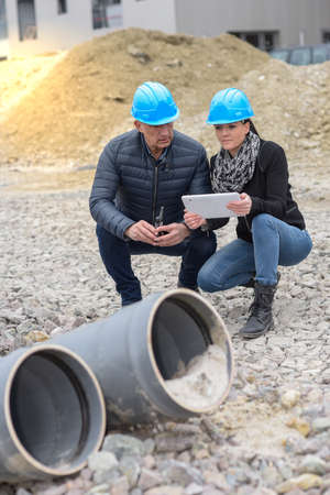 Construction manager and architect read their notes on a tablet on a buildding siteの写真素材