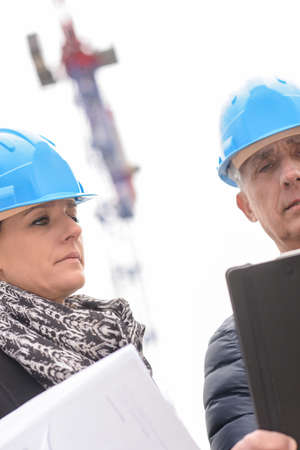 Construction manager and architect on a buildding site beside a construction craneの写真素材