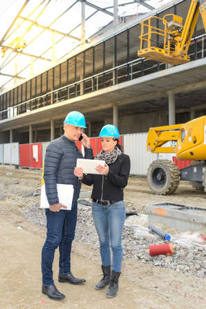 Construction manager and architect reading their notes on a tablet in front of a metallic constructionの写真素材