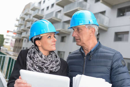 Construction manager and architect read notes in front of a loader backhoeの写真素材