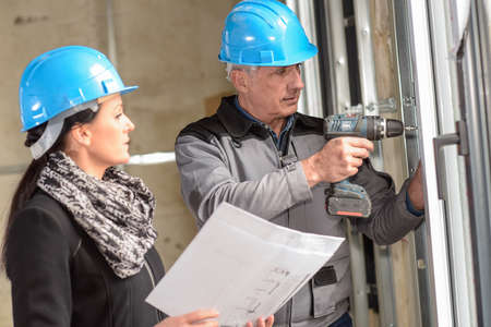 Construction manager and architect read notes in front of a loader backhoeの写真素材