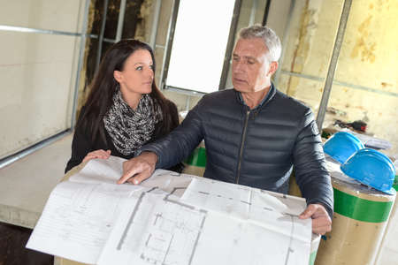 Construction manager and architect read notes in front of a loader backhoeの写真素材