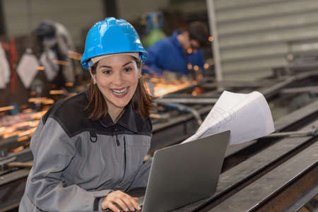 Confident woman engineer checks a blueprint at workの写真素材