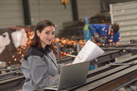 Confident female engineer checks her laptop in the factoryの写真素材