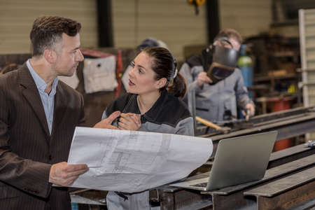 The factory owner is giving orders to his female workerの写真素材