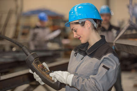 Positive female worker operates heavy machinery in factoryの写真素材