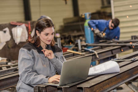 Confident female engineer checks her laptop in the factoryの写真素材
