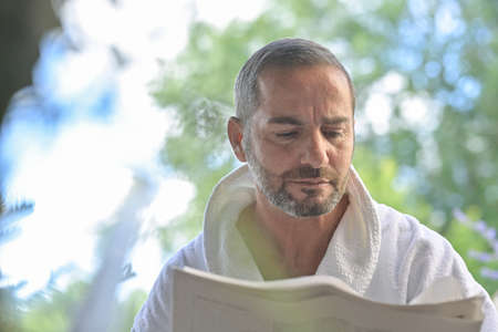 Portrait of a man wearing a bathrobe and reading the morning news on a newspaper