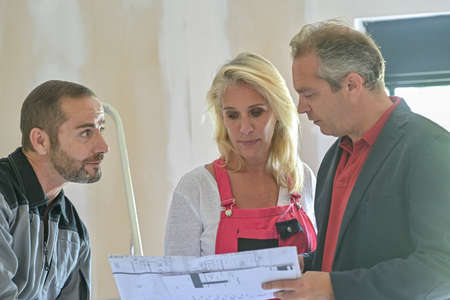 Discussion around the plan of an architect between the construction manager and the craftsmen involved in the renovation of a houseの写真素材