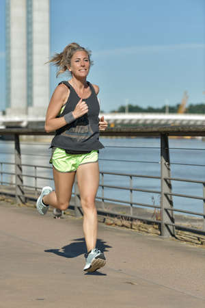 Female jogger during her running session along a river in the cityの写真素材