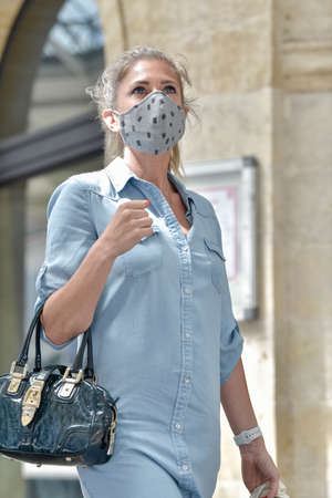 Urban woman doing shopping while she is wearing a protective mask in the street against coronavirusの写真素材