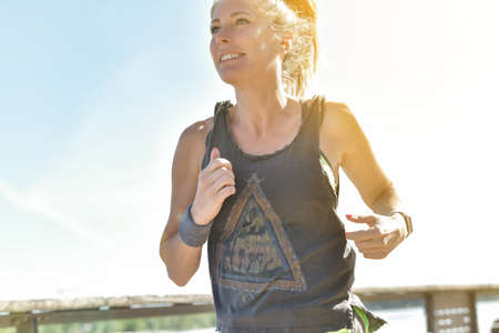 Female jogger during her running session along a river in the cityの写真素材