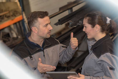 Two workers are checking the tablet while working in a metal warehouseの写真素材