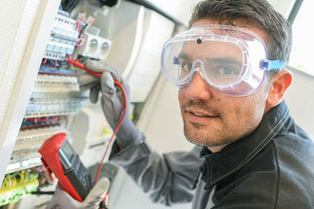 Electrician tests circuit breakers in a electrical panelの写真素材