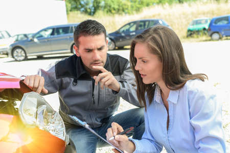 Female expert and male car body worker checking the cost of a car reparationの写真素材
