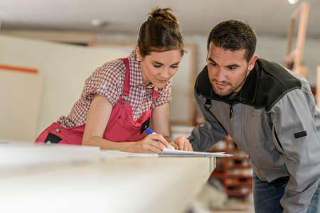 Female and male wood workers checking paperwork in workshopの写真素材