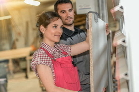 Male worker teaching female apprentice how to operate a machineの写真素材
