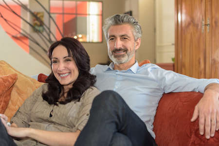 Happy middle-age couple watching a film togetherの写真素材