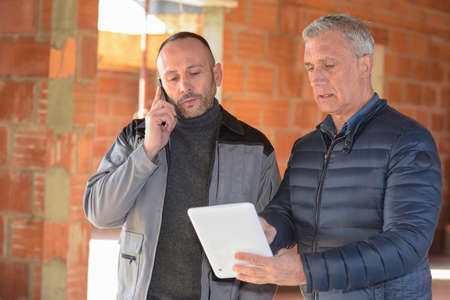 Architect and contractor looking at plans on a building siteの写真素材