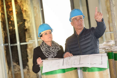 Architect and his assistant on a renovation site are checking a blue-print