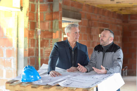 Architect and contractor looking at plans on a building siteの写真素材