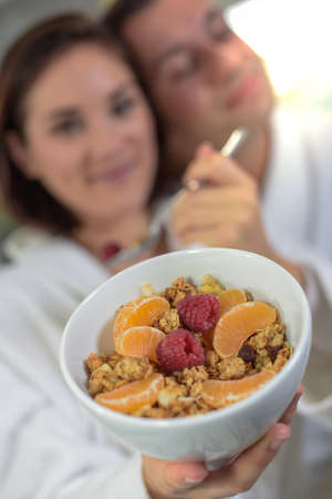 happy woman in bathrobe showing a healthy bowl of cerealsの写真素材