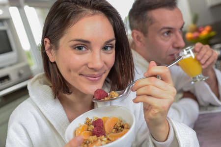 Young couple in bathrobes takes a healthy breakfast in the kitchenの写真素材