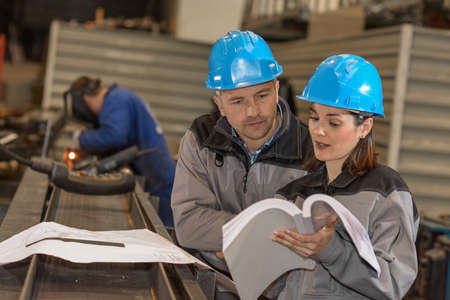Colleagues are discussing a technical information for a new metallic construction over the blueprintの写真素材