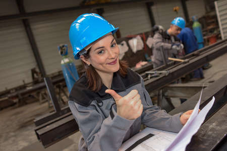 Confident female engineer checks the blueprint in the factoryの写真素材