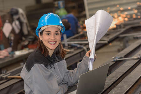 Confident female engineer checks her laptop in the factoryの写真素材