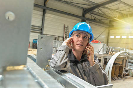 Woman worker is calling on her phone in the workshopの写真素材