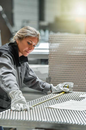 Woman worker measuring a metallic piece in the workshopの写真素材