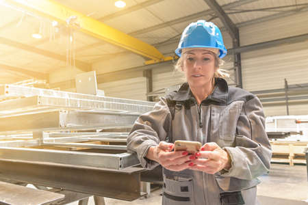 Woman worker is reading her sms in the workshopの写真素材