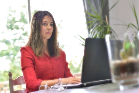 Young woman working at home and attending a meeting on her laptop.の写真素材