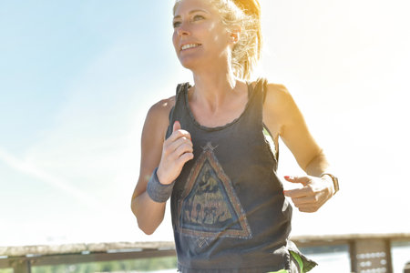 Female jogger during her running session along a river in the city