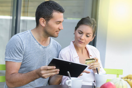 Happy couple using a tablet and paying onlineの写真素材