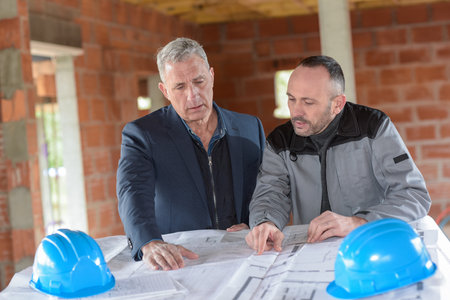 Architect and contractor looking at plans on a building siteの写真素材