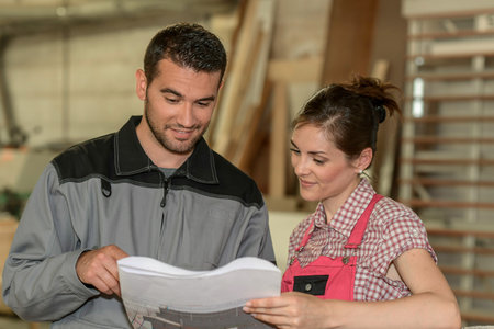 Female and male wood worker checking paperwork in workshop
