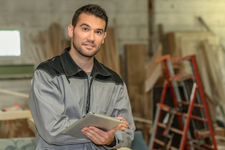 Carpenter checks the plans of the project on his tabletの写真素材