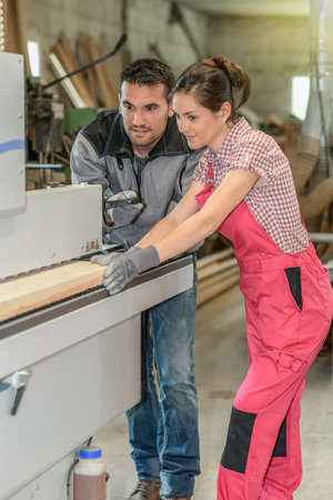Male worker teaching female apprentice how to operate a machineの写真素材