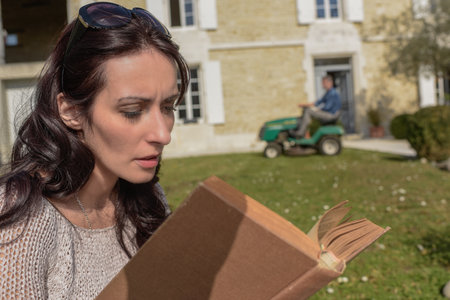 Wife takes advantage of husband to pass lawn tractor to relax and readの写真素材