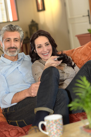 Happy middle-age couple watching a film togetherの写真素材