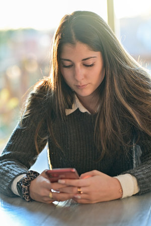 Female teenager student is browsing on his mobile at home or chatting with a friend on a social network with a mobile applicationの写真素材