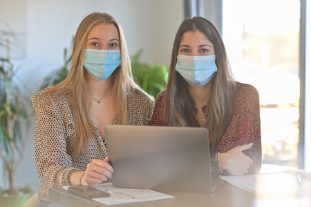 Young female students are working together at home and are wearing protective mask due to the covid-19の写真素材