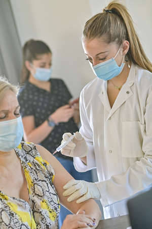 Injection of the vaccine against the covid-19 by a doctor and a nurse in a vaccination centerの写真素材