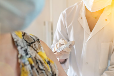 Injection of the vaccine against virus by a doctor and a nurse in a vaccination centerの写真素材