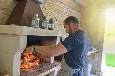 Man grilling meat on the barbecue in a chimneyの写真素材