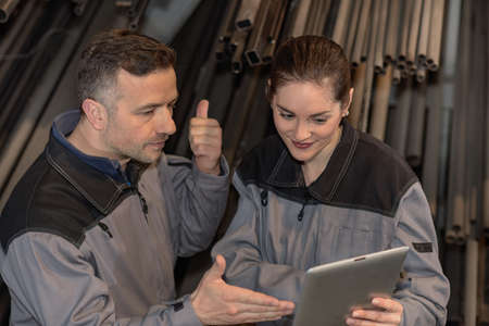 Female metal warehouse worker is showing something to her supervisorの写真素材