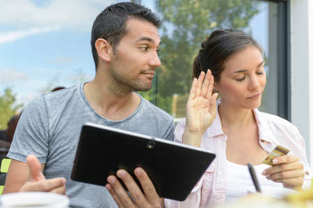 Happy couple using a tablet and paying onlineの写真素材