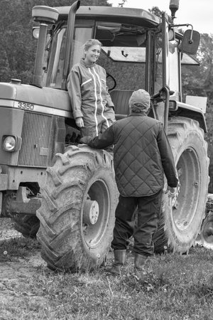 Woman farmer listening the instruction from her boss before to leave the farm with her tractorの写真素材